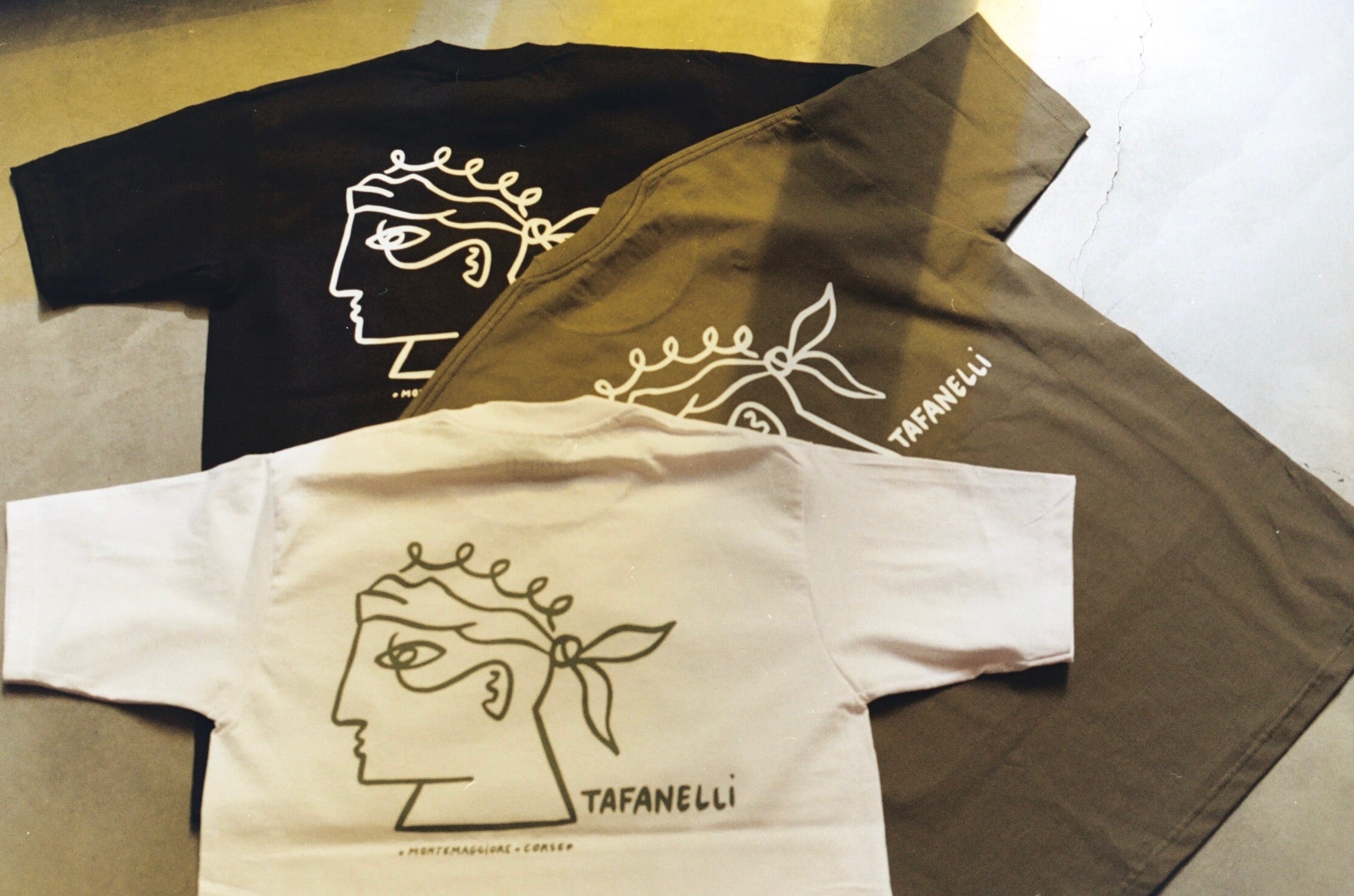 T-shirt Tafanelli en coton biologique reposant sur un tissu brut, prêt à être lavé avec soin pour préserver sa forme et sa texture naturelle.